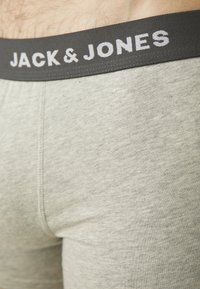 Graue Boxershorts mit einem schwarzen elastischen Bund, der "JACK & JONES" in Weiß aufgedruckt hat. Weicher, elastischer Stoff mit glatter Textur.