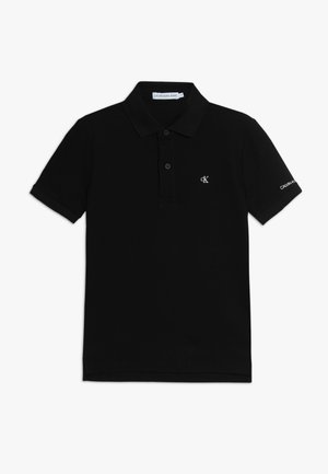 Czarna koszulka polo z krótkim rękawem, kołnierzykiem, dwoma przednimi guzikami, małe białe logo "cK" na piersi oraz tekst "Calvin Klein" na rękawie.