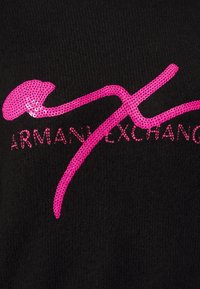 Schwarzer Stoff mit einer strukturierten Oberfläche, auf dem ein großes, glänzendes rosafarbenes Logo in kursiver Schrift zu sehen ist, das "ARMANI EXCHANGE" liest.