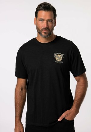 Sort bomulds T-shirt med korte ærmer. Har et beige grafisk design af en ørn og tekst på brystet. Lige skåret design. Blød tekstur.