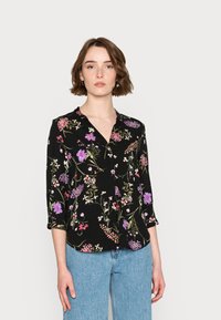 Blusa preta com um padrão floral apresentando flores roxas, brancas e rosas; decote em V e mangas de três quartos. Tecido suave.