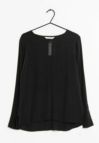 Blouse noire à manches longues avec un col rond, un panneau avant transparent et des fentes latérales. Fabriquée en tissu léger et lisse.