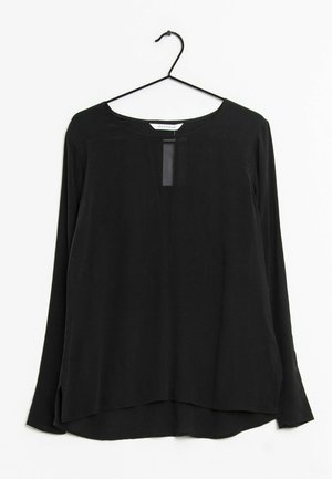 Blusa nera a maniche lunghe con scollatura rotonda, pannello anteriore trasparente e spacco laterale. Realizzata in tessuto leggero e liscio.