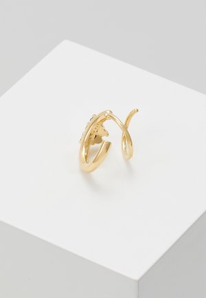 Oorbellen van open twisted hoepel in goudkleur met een gladde afwerking, gepresenteerd op een wit geometrisch platform tegen een grijze achtergrond.