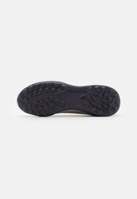Semelle en caoutchouc noir d'une chaussure de sport avec des grips texturés et des motifs cannelés. Présente le mot "PREDATOR" en relief sur la surface.