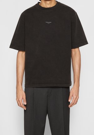 Czarny, oversize’owy T-shirt wykonany z miękkiego materiału, z okrągłym dekoltem, krótkimi rękawami oraz małym białym logo na piersi.