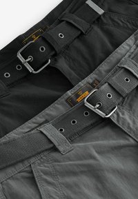 Mørkegrå cargoshorts med et struktureret bælte med metalspænde, flere øjer og syede labels langs taljen.