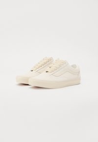 Off-white színű vászon, alacsony szárú sportcipők, texturált anyaggal, kerek fűzőkkel és gumitalppal, amely texturált tapadási részletekkel rendelkezik.