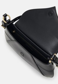 Svart läderhandväska med en strukturerad design, guldiga detaljer och en zippered inre ficka. Lucka upptill för enkel åtkomst.