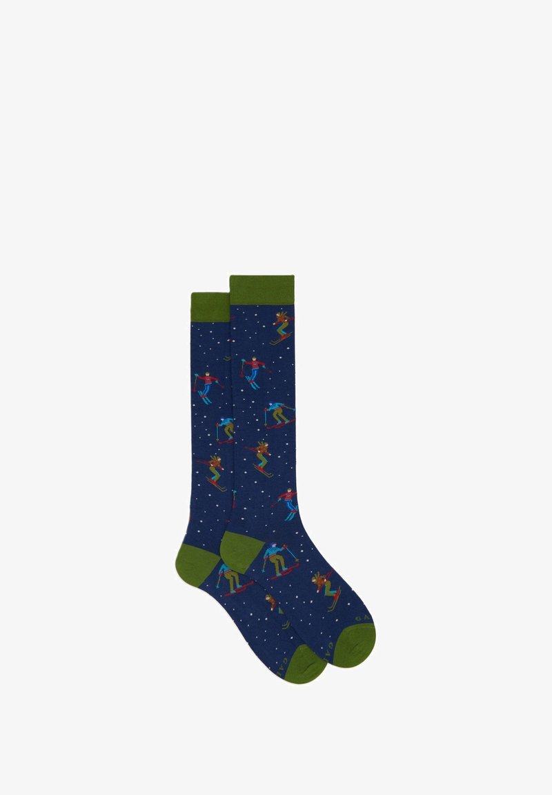 Calze fino al ginocchio in blu navy con polsini verdi, decorate con figure colorate di sciatori e fiocchi di neve su tutta la stoffa.