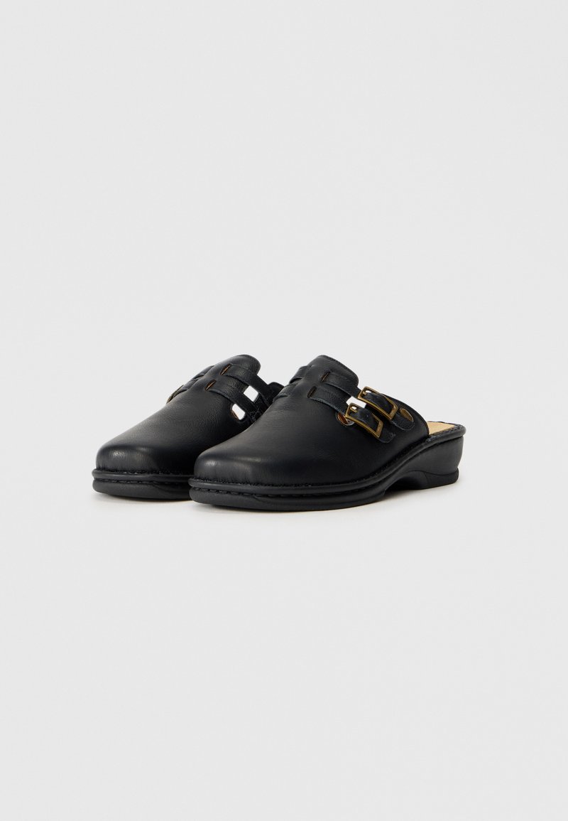Sabots en cuir noir avec un bout arrondi, accents de double boucle et semelle intérieure rembourrée. Texture lisse avec un léger éclat.