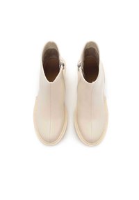 Bottines beige en cuir lisse, dotées d'une fermeture éclair sur le côté, d'un bout rond et d'une semelle légère avec des détails de couture.