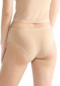 Beige Baumwoll-Hipster-Unterwäsche mit einer glatten Textur, ausgestattet mit einem weichen Bund und minimalen Nähten, von hinten betrachtet.