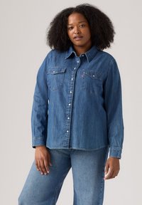 Denimhemd, mittlerer Waschung, lange Ärmel, spitzes Kragen, zwei Brusttaschen, Knopfverschluss, leicht abgerundeter Saum, lässige Passform.