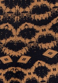 Tissu tricoté noir et marron avec des motifs géométriques comprenant des diamants et des formes abstraites dans un dessin symétrique répétitif.