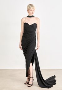 Melnā strapless kleita ar rievoto faktūru, asimetrisku apak�šmalu un augstu šķēlumu. Akcentēta ar atbilstošu kakla rotu un valkāta ar melnajiem sandālēm uz siksniņām.