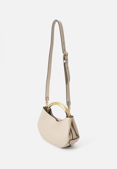 Sac à main en cuir beige avec une forme arrondie, doté d'une poignée en métal doré et d'une bandoulière réglable. Texture lisse avec des accents minimaux.