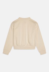 Sudadera beige con un cuello alto, mangas largas y dobladillo fruncido. Fabricada con un tejido suave y con puños acanalados. Diseño minimalista.