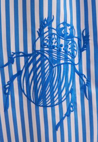 Design ricamato blu che mette in mostra una figura a forma di cuore su un tessuto a righe blu e bianco. Presenta dettagli intricati e una superficie liscia.
