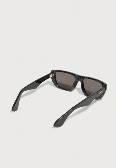 Rectangular black sunglasses with dark lenses and wide temples, placed face down on a white surface.