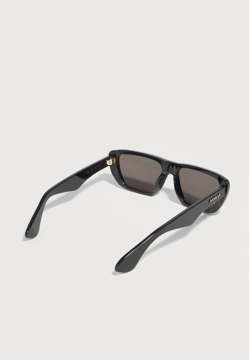 Rectangular black sunglasses with dark lenses and wide temples, placed face down on a white surface.
