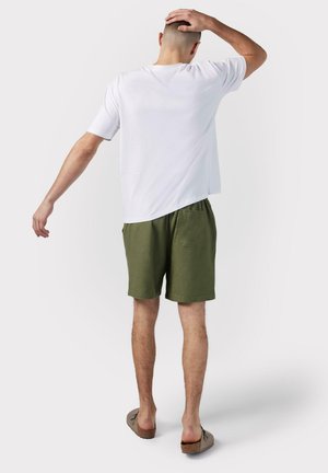 Witte kortemouwen shirt, olijfgroene shorts en bruine instappers. Eenvoudig ontwerp, relaxte pasvorm en casual styling.