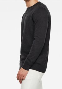 Pull à manches longues gris foncé en matière douce, avec un col rond, des poignets côtelés et une coupe ajustée.