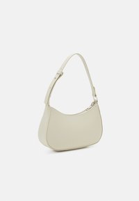 Béžová kožená kabelka s zakřiveným tvarem, nastavitelným popruhem a zapínáním na zip. Hladká textura s minimálními kovovými doplňky.