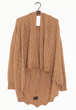 Brauner gestrickter Schal mit einem strukturierten Zickzackmuster, offenem Frontbereich und gewelltem Saum, hängt an einem schwarzen Haken vor einem weißen Hintergrund.