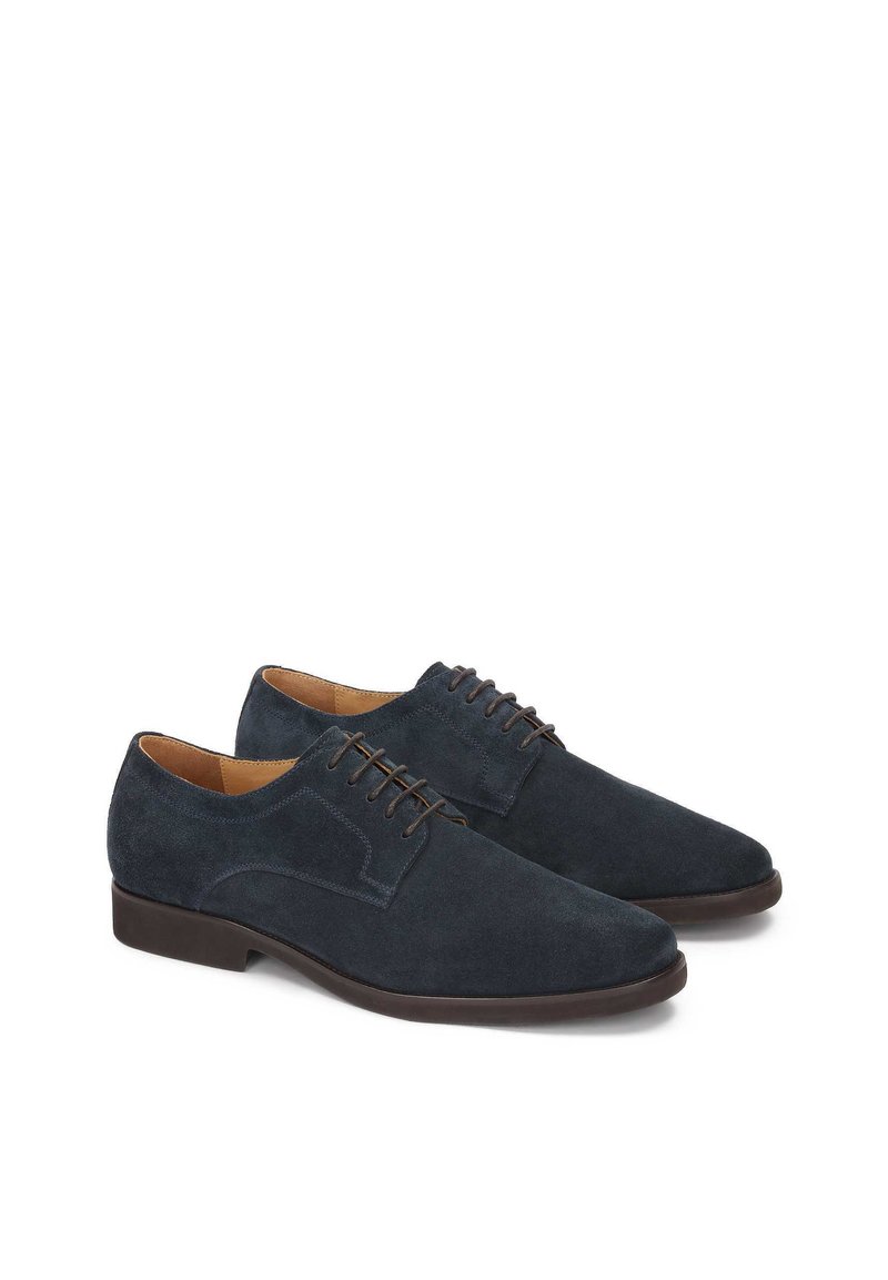 Chaussures en daim bleu foncé avec une texture lisse, à bout pointu et lacets marron. Présente un accent minimal en couture sur le côté.