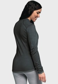 Dunkelgraues Langarmshirt aus strukturiertem Stoff, mit rundem Halsausschnitt und Flachnähte, kombiniert mit hellgrauen Hosen.