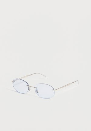 Lunettes ovales sans monture avec des verres teintés bleu clair et des branches métalliques fines et argentées, reposant sur une surface blanche.