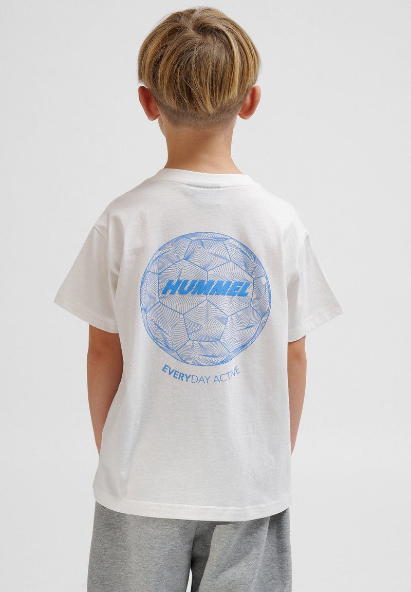 T-shirt en coton blanc comportant un graphique de ballon de football bleu au dos avec le texte "HUMMEL" et "EVERYDAY ACTIVE" en dessous. Manches courtes, col rond.