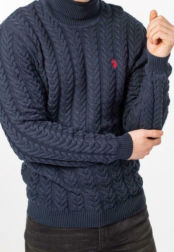 Navyblå kabelstickad tröja med hög krage, ribbade kanter och en liten röd logotypdetalj på vänster bröst. Mjuk texturerad tyg.