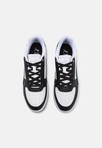 Sorte og hvide sneakers med rund tå, perforeret design, sorte snørebånd og en grøn accent på siden. PUMA-logo på tungen og indersålen.