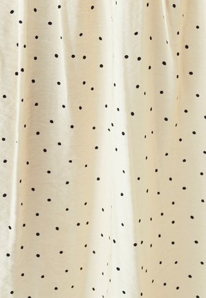 Krémová tkanina s černými puntíky, s jemnou strukturou a lehkým splývavým vzhledem. Puntíky se liší velikostí a jsou rovnoměrně rozmístěny.