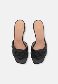 Melnas ādas slaidu sandales ar divu siksnu dizainu, kvadrātveida purngalu un zelta sirds logotipu uz iekšējās zoles. Gluda tekstūra un minimālisma stils.