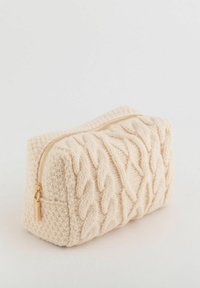 Kremowa dzianinowa kosmetyczka z wzorem warkocza, złotym suwakiem i prostokątnym kształtem. Miękka w dotyku z usztywnionymi bokami.