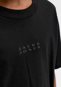 Czarny t-shirt z krótkim rękawem wykonany z bawełny, z subtelnym tonalnym logo "JACK & JONES" na klatce piersiowej oraz okrągłym dekoltem.