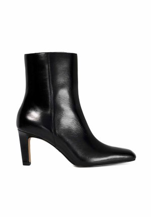 Bottine en cuir noir avec un embout pointu et un talon haut fin et structuré. Texture lisse avec un design minimaliste et sans ornements visibles.