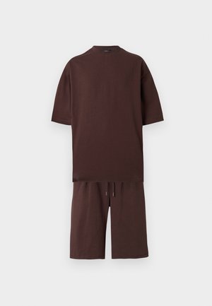 Bruin katoenen oversized T-shirt met korte mouwen, gecombineerd met bijpassende sweatshorts met aantrekkoord, plat weergegeven op een witte achtergrond.