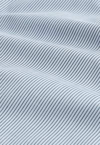 Helles blaues Gewebe mit feinen schwarzen Streifen, das eine glatte Textur und ein subtile Wellenmuster aufweist, erzeugt dreidimensionale Falten auf der Oberfläche.