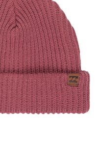 Gorro de punto en rosa empolvado con un puño doblado. Presenta una textura acanalada y una pequeña etiqueta de cuero marrón con un logo.