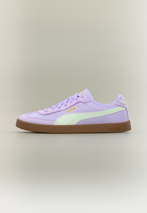 Πλάγια όψη ενός sneaker Puma λεβάντας με ανοιχτοπράσινη ρίγα και καφέ σόλα σε ουδέτερο φόντο.
