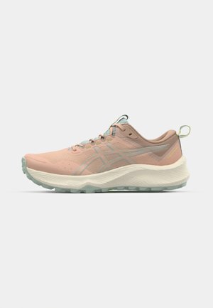 Zapatilla de running rosa claro con parte superior de malla transpirable, detalles en verde y una entresuela blanca texturizada. Cuenta con una suela exterior de goma flexible.