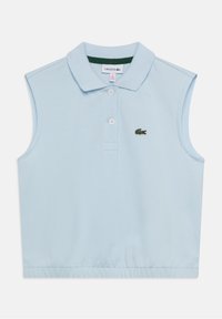 Ljusblå ärmlös pikétröja med krage, två knappar och en grönaccentuerad halsringning. Lacoste-logotyp broderad på vänster bröst.