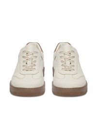 Białe skórzane sneakersy z brązową gumową podeszwą, teksturowanym bieżnikiem i beżowymi sznurówkami. Posiadają zaokrąglony czubek i przeszywane akcenty.