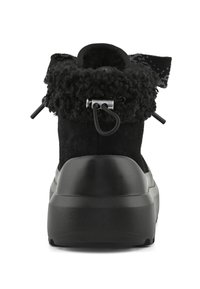 Černé nubukové kotníkové boty s texturovaným límcem z umělé kožešiny, zaobleným podpatkem a kovovým detailem na zadní straně.
