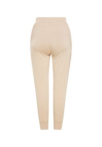 Beige katoenen joggers met een zachte textuur, taps toelopende pijpen, elastische tailleband en opgerolde enkels, gezien vanaf de achterkant.