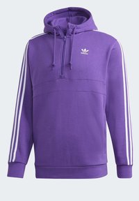 Lila fleecehuva med en halv dragkedja framtill, justerbar huva och vita tre-strimmor på ärmarna. Liten vit logga på bröstet.